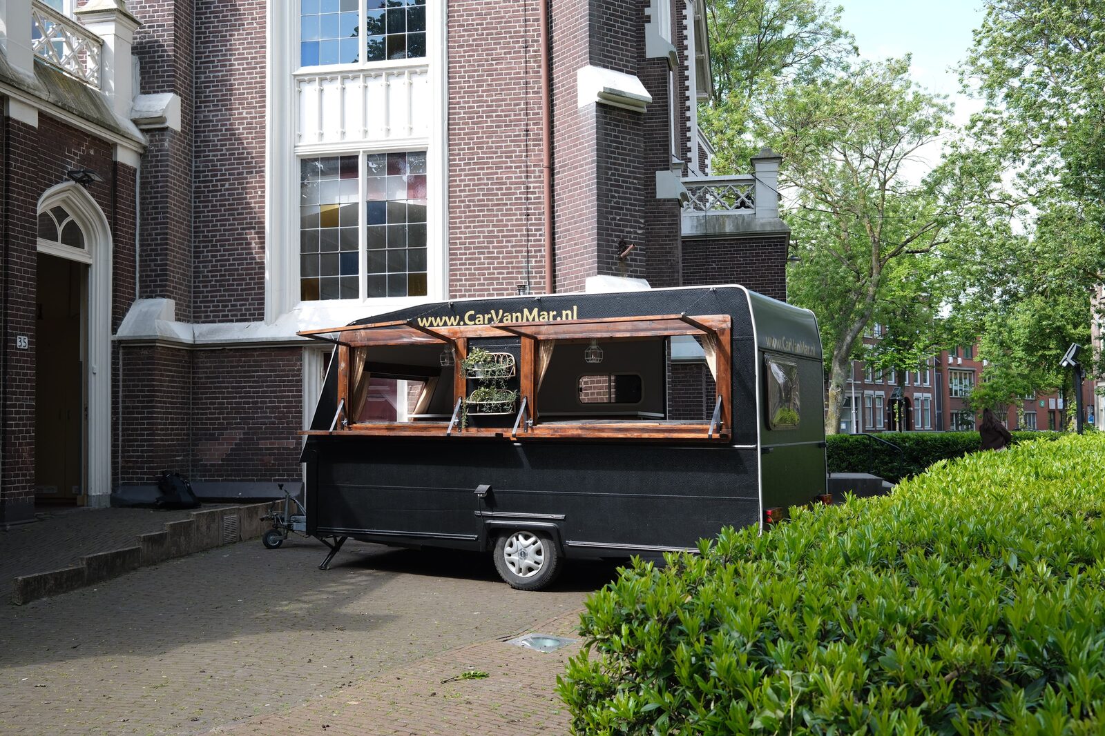 Zijaanzicht van de zwarte CarVanMar foodcaravan met serveerluik